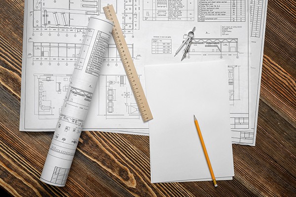 Blueprints on wooden table background with a pencil, a ruler and compasses lying beside.bou